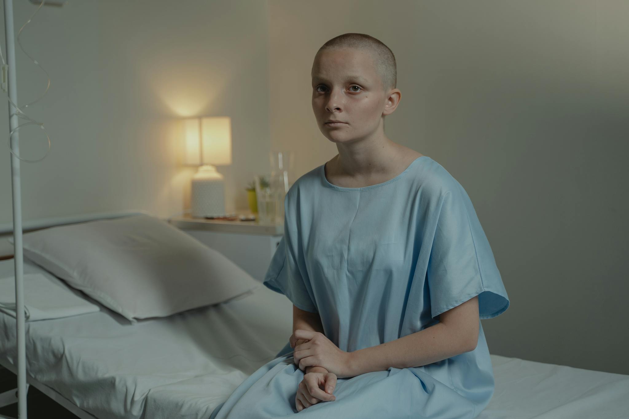 A young patient in a hospital room wearing a blue gown, conveying a calm mood.